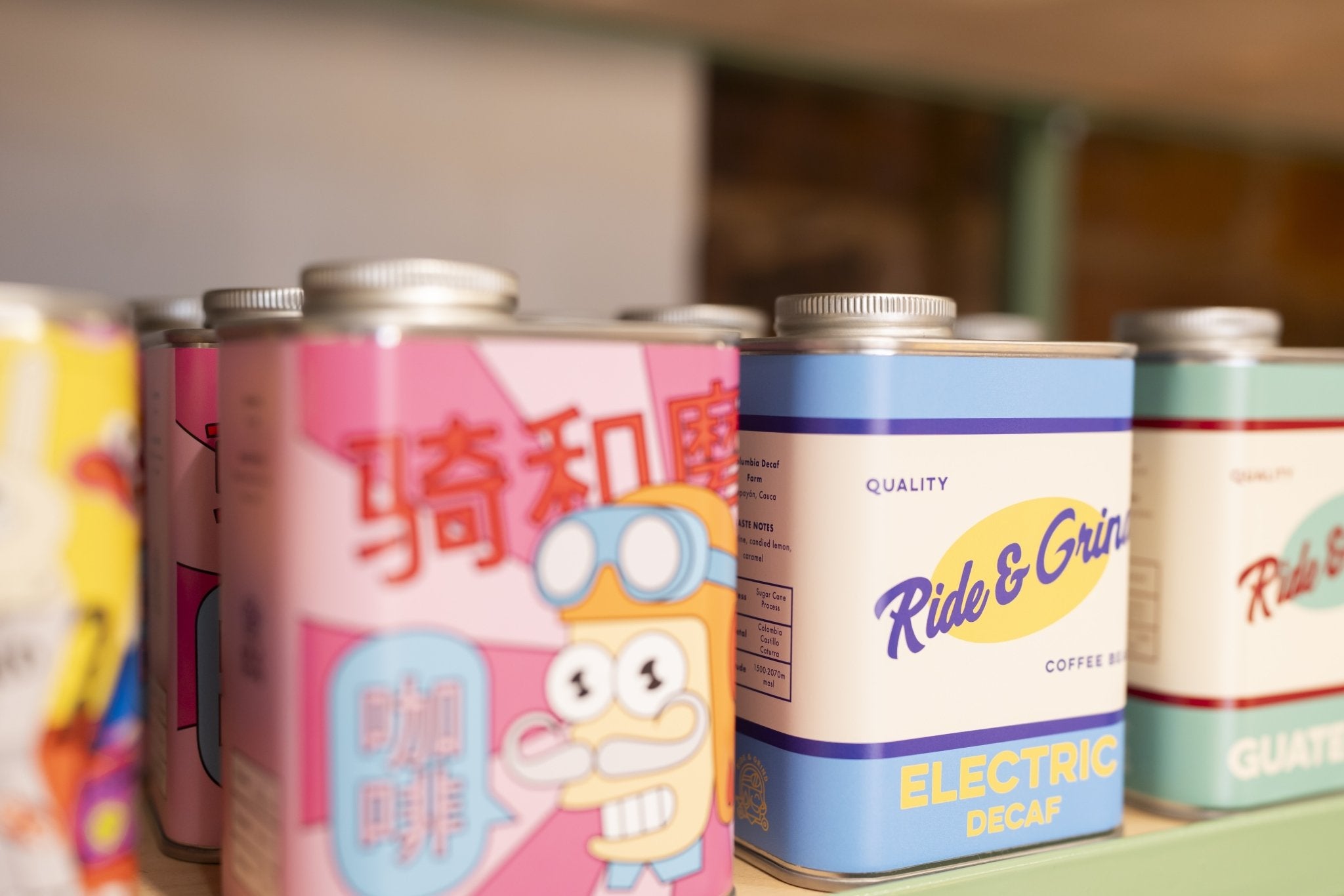 Row of colorful coffee cans with various designs and branding.